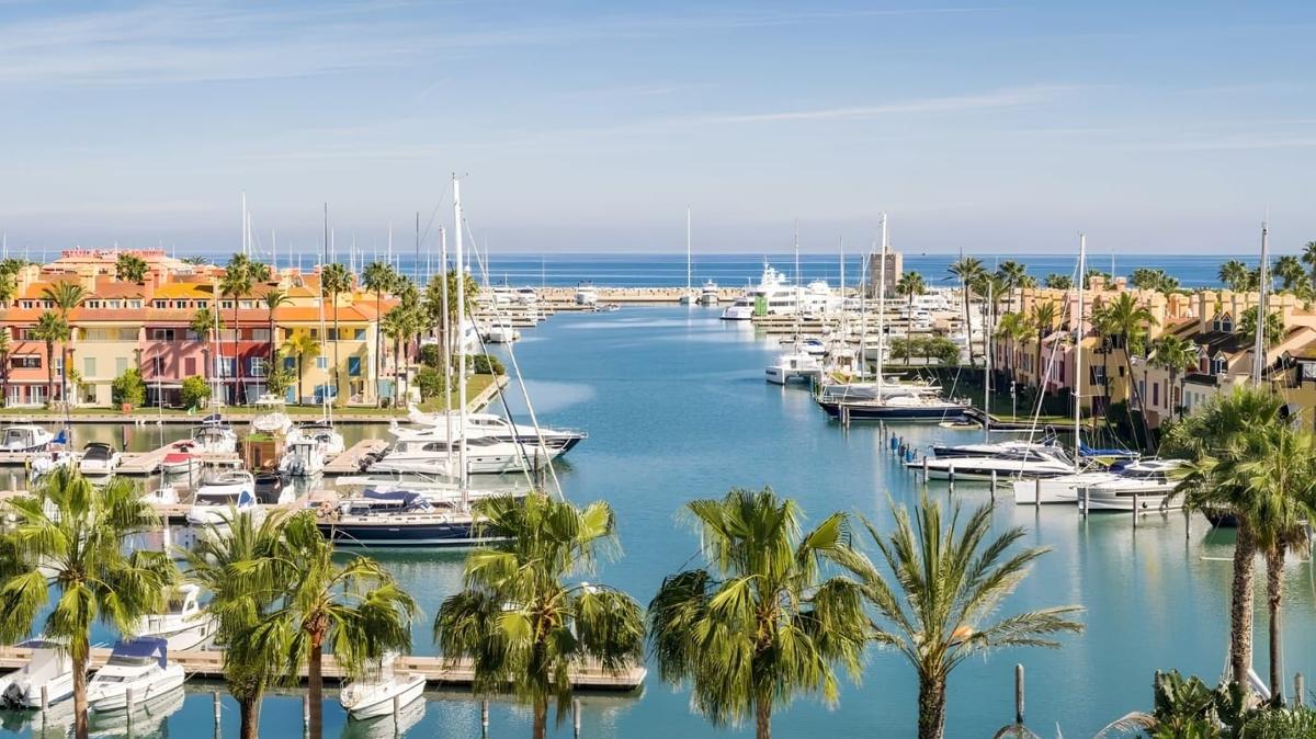 The Sotogrande marina in soft Andalusian light, palm-lined canals leading out to the Mediterranean — the 1962-planned community that quietly holds the highest-spend Spanish trophy addresses outside the islands.