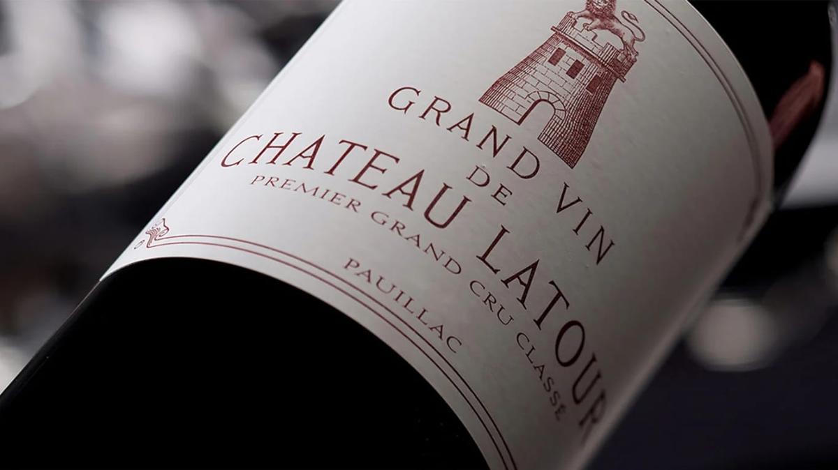 A bottle of Grand Vin de Château Latour Premier Grand Cru Classe from Pauillac lying on its side, its cream label showing the estate lion and tower crest in deep red.