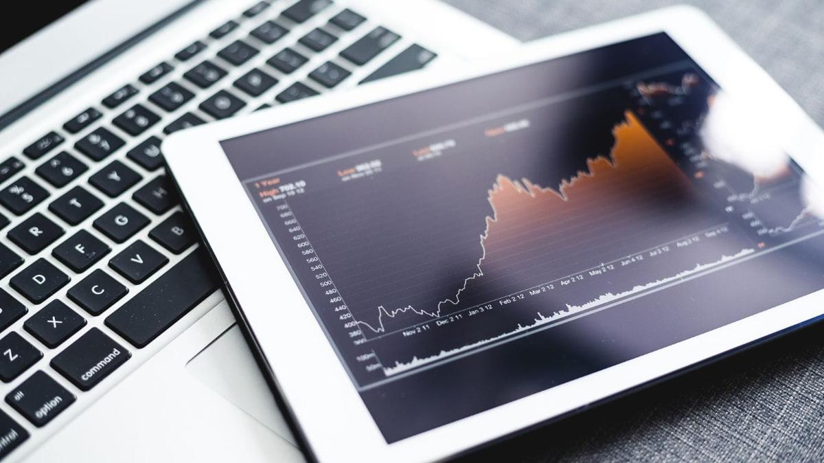 A tablet placed on top of a laptop, displaying a dividend stock chart on its screen