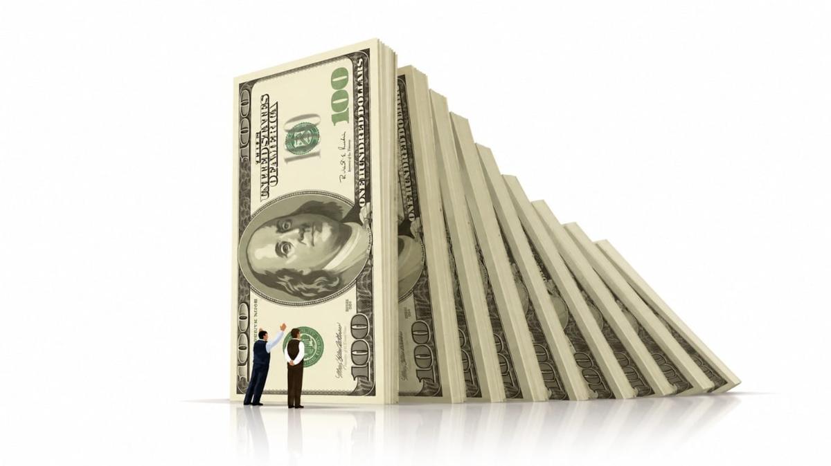 A hundred dollar bill holding up a line of toppling banknote dominoes, an image of judgment, risk and value in investing.