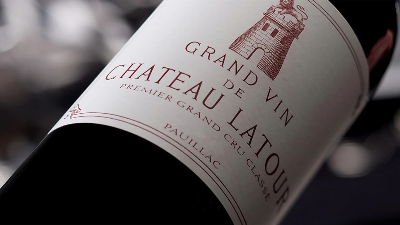A bottle of Grand Vin de Château Latour Premier Grand Cru Classe from Pauillac lying on its side, its cream label showing the estate lion and tower crest in deep red.