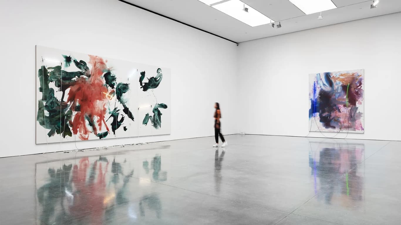 A visitor walking through a Gagosian gallery, large gestural abstract canvases on the white walls reflected in the polished concrete floor.