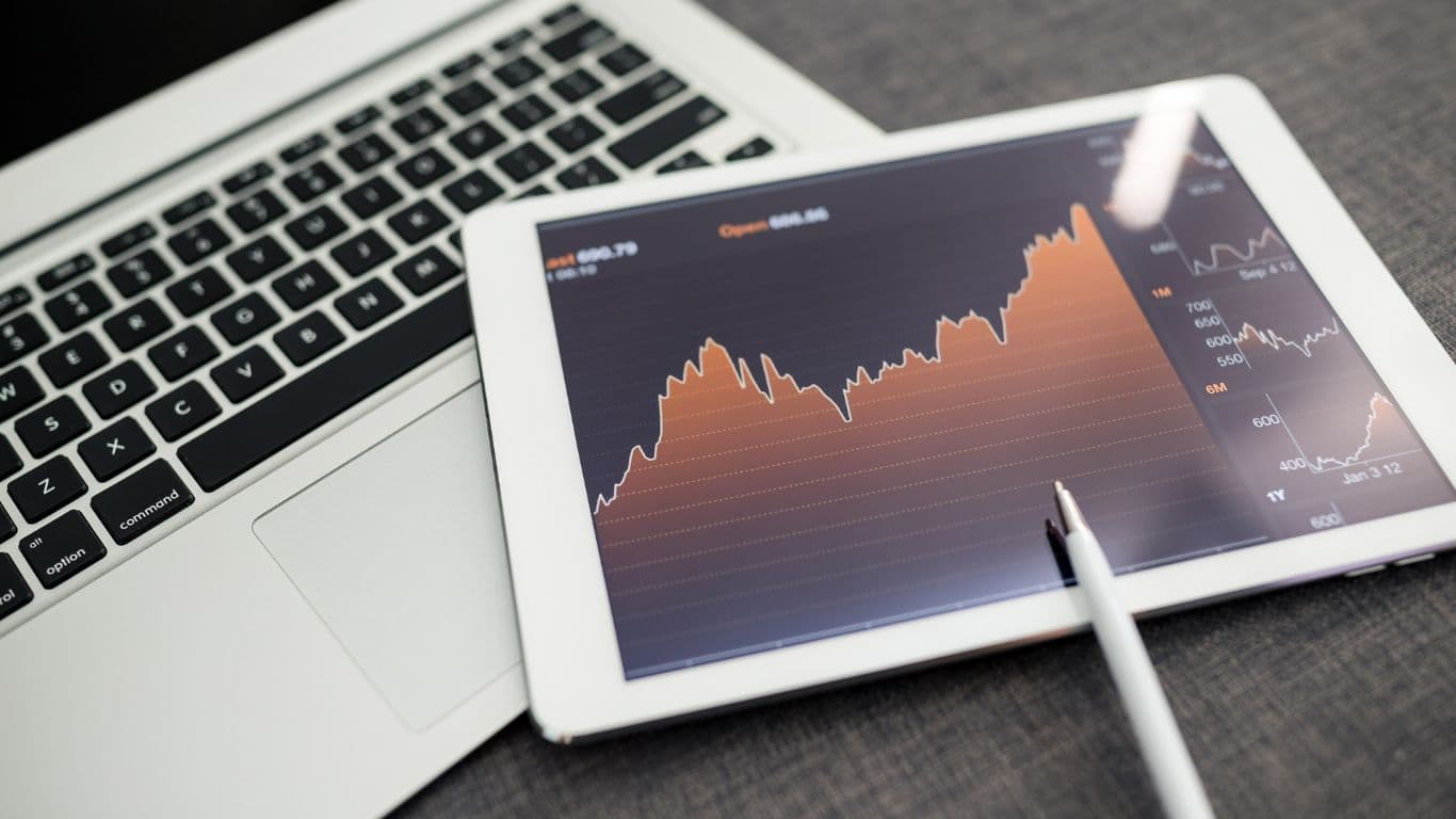 A tablet placed on a laptop displaying a dynamic chart illustrating Index Rebalancing in progress