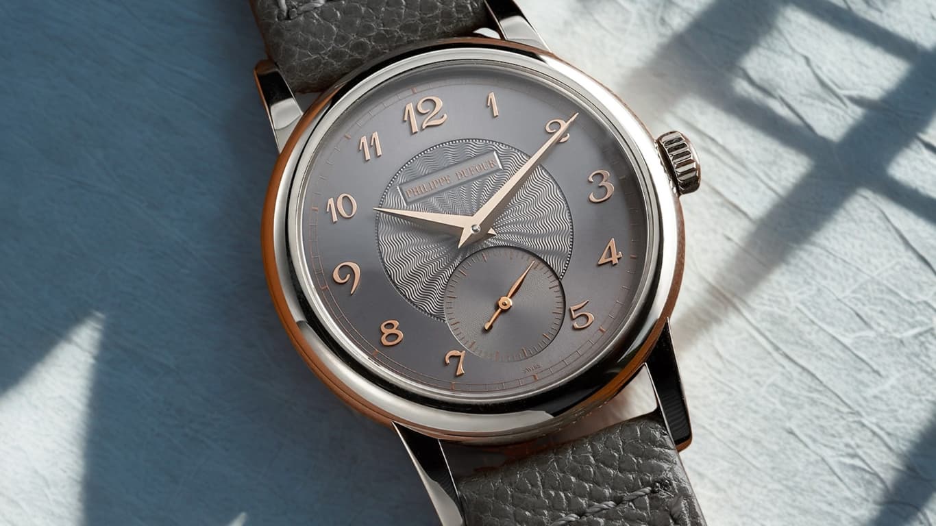 A Philippe Dufour Simplicity in white gold on a grey strap, its grey guilloche dial with rose gold Breguet numerals and a small seconds subdial.