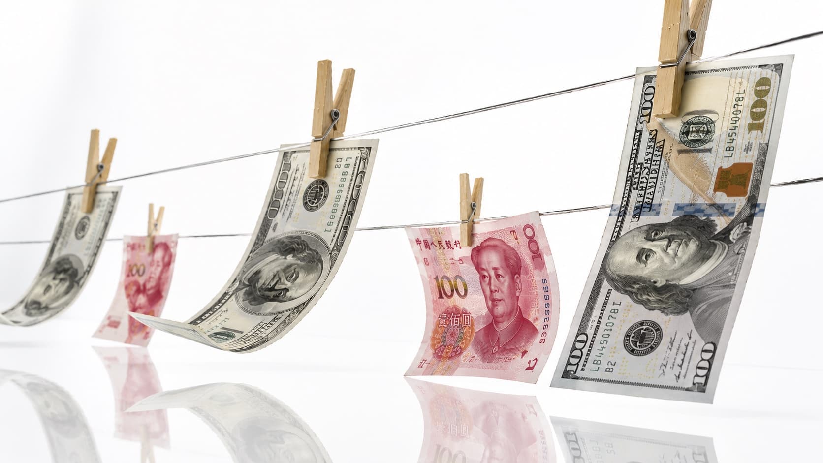 US dollar and Chinese yuan banknotes pinned to washing lines with wooden clothespins, the classic image of money laundering.