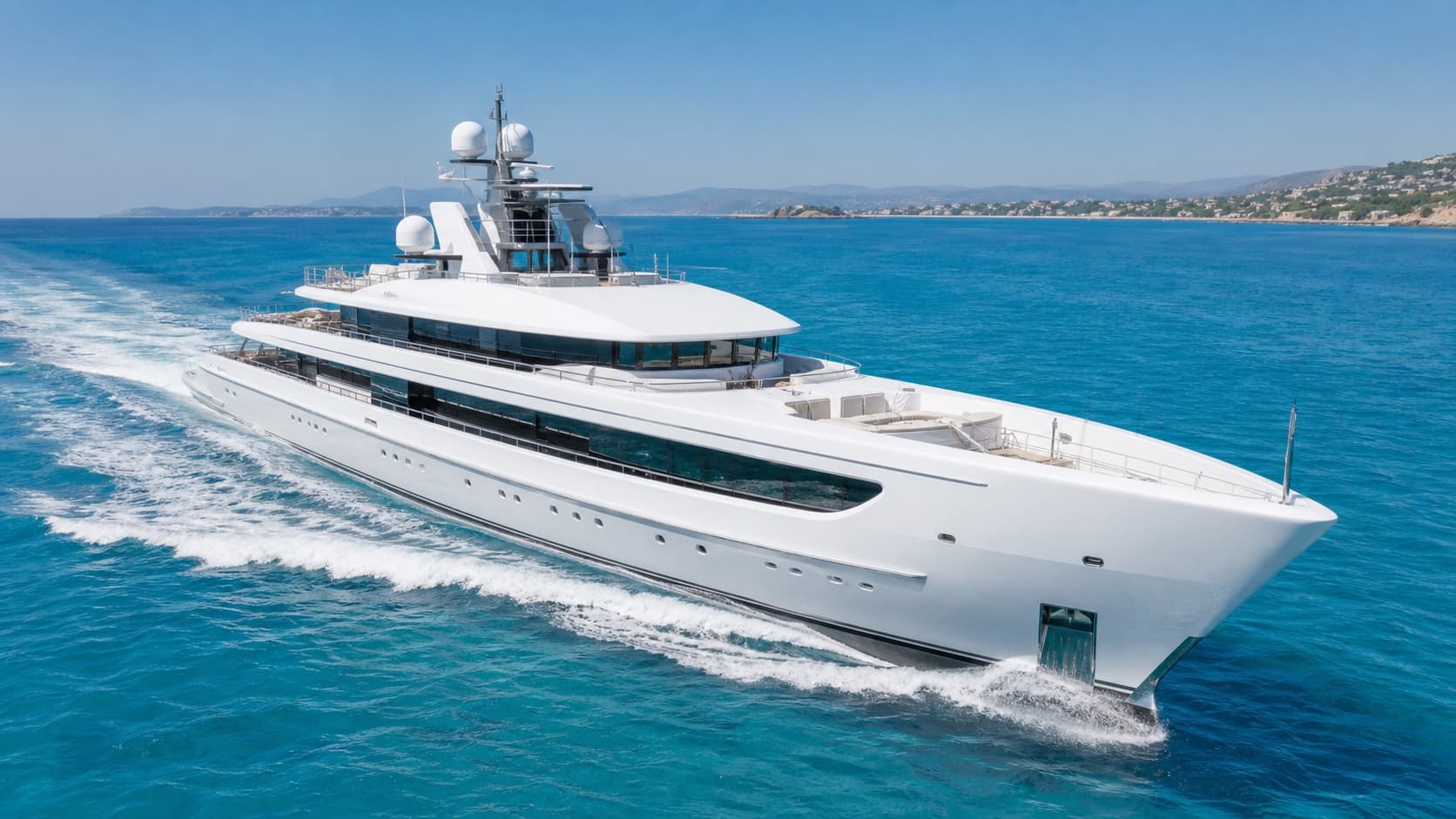 A large white superyacht cruising through sunny Mediterranean waters