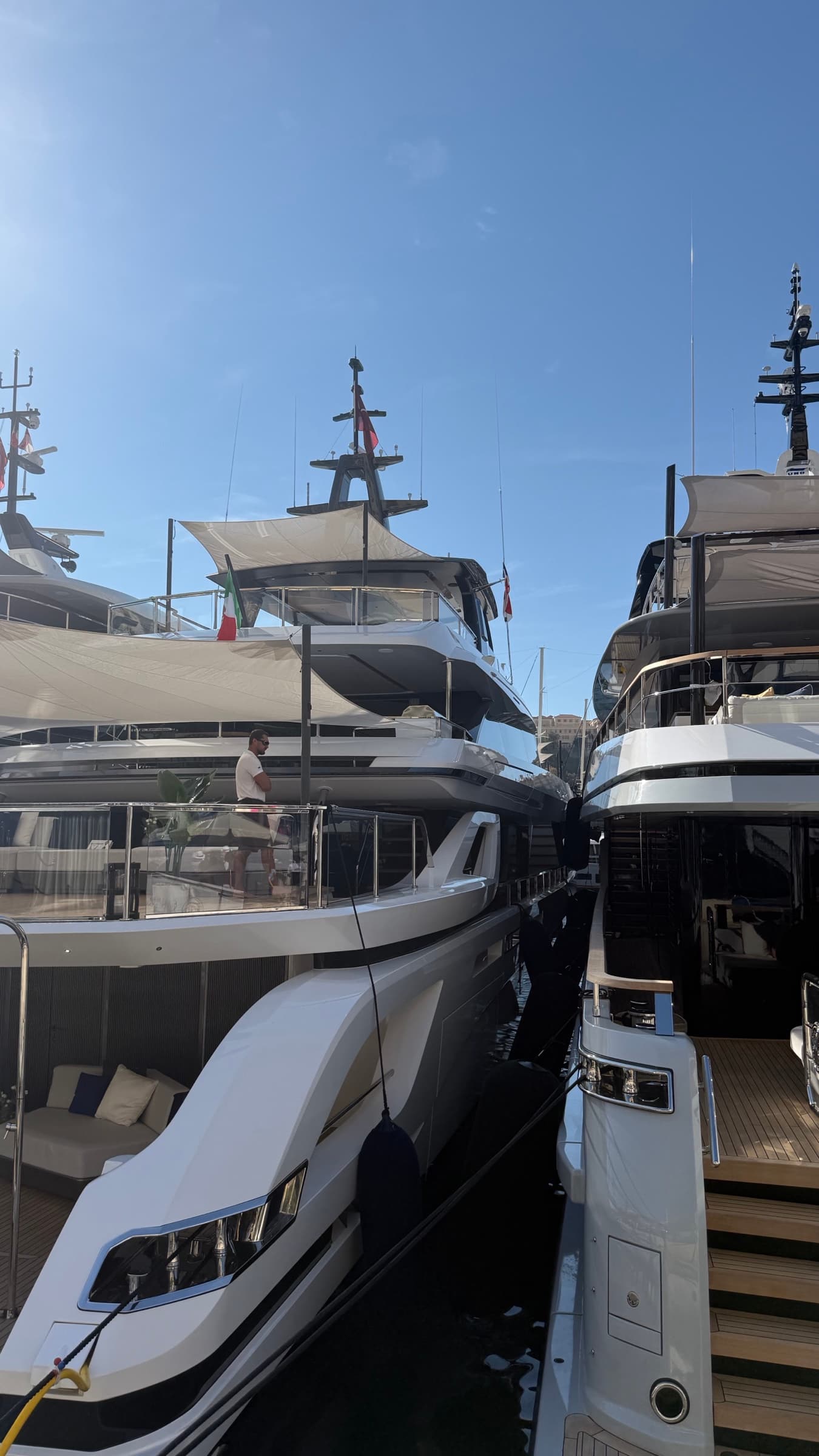 Several superyachts and international flags at the Monaco Yacht Show marina.