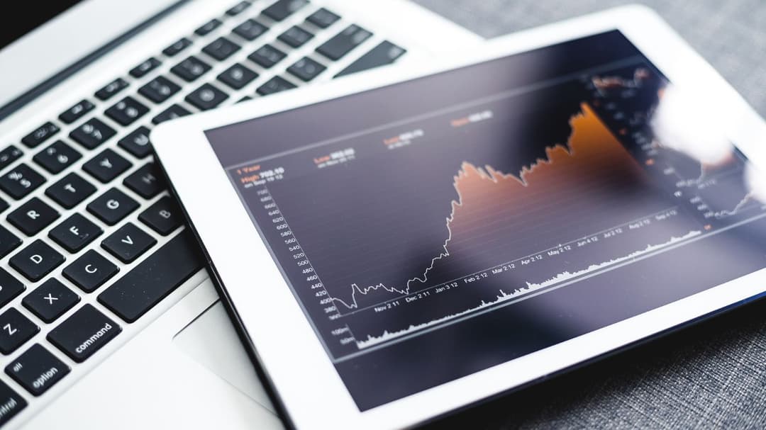A tablet placed on top of a laptop, displaying a dividend stock chart on its screen