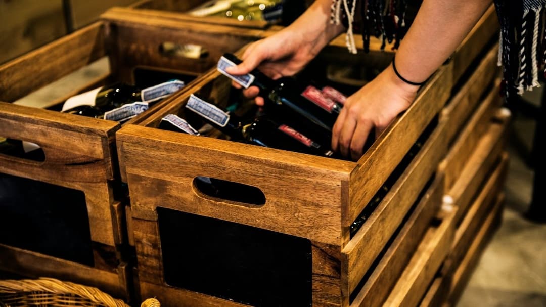 a person holding a bottle of wine in a wooden crate