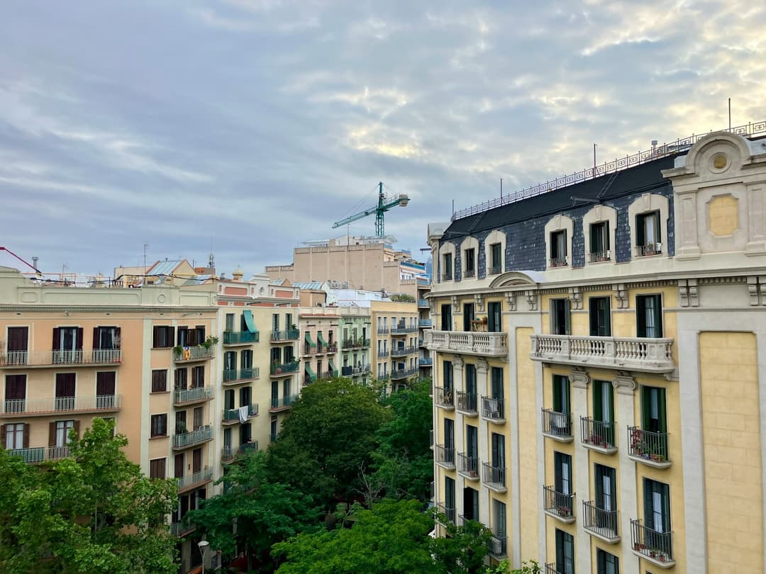Classic Eixample apartment facades in Barcelona with wrought iron balconies above a tree lined inner street.
