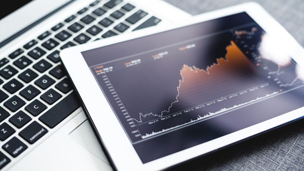 A tablet placed on top of a laptop, displaying a dividend stock chart on its screen
