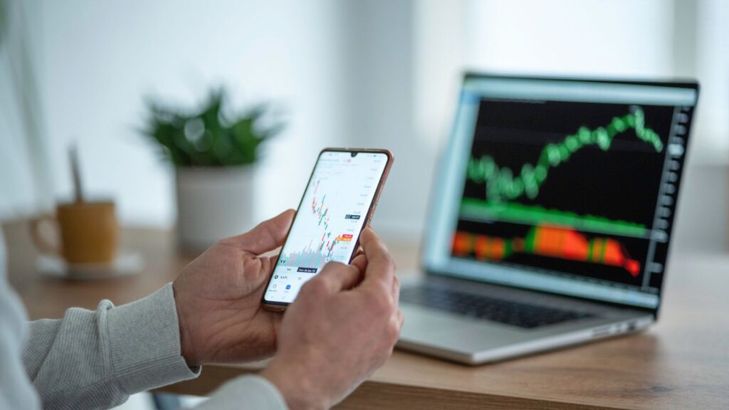 A person holding a cellphone, closely watching a chart of a dividend stock on the screen