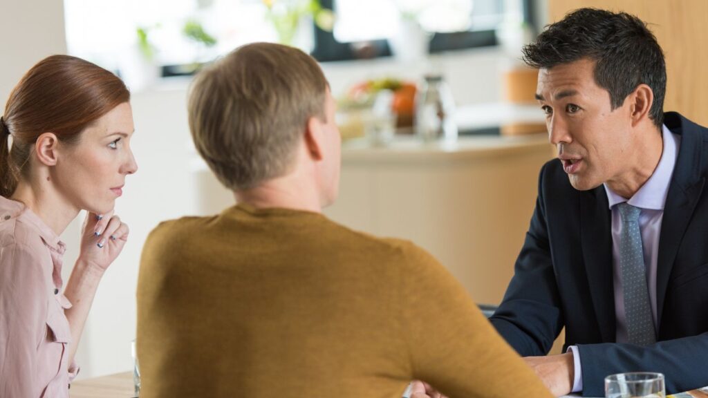 A financial advisor meets with a couple, discussing their financial plans and options. The advisor actively engages with them, guiding the conversation to address their specific needs and goals.